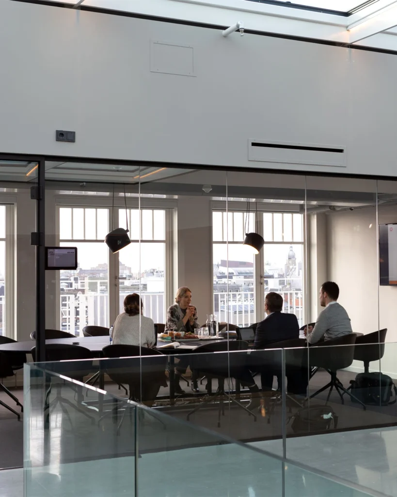 Business meeting in a glass-walled conference room at a modern Stockholm office