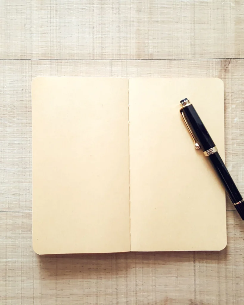 Open notebook and fountain pen on a light wooden desk