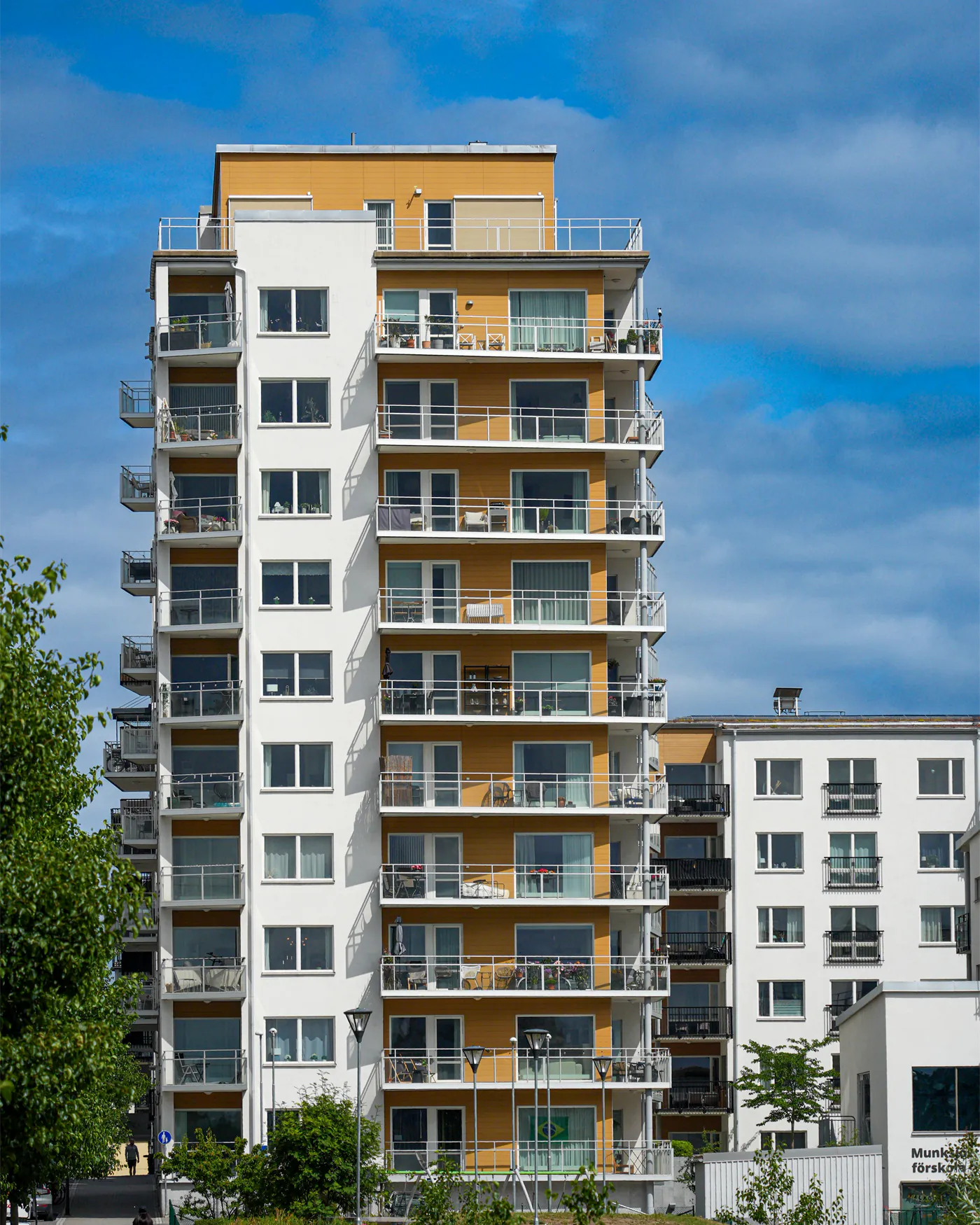 Modern Swedish apartment building with balconies and trees under a clear sky