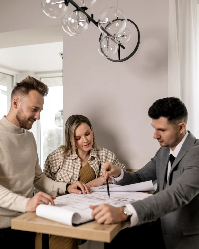 Three people going through property plans and documents at a table