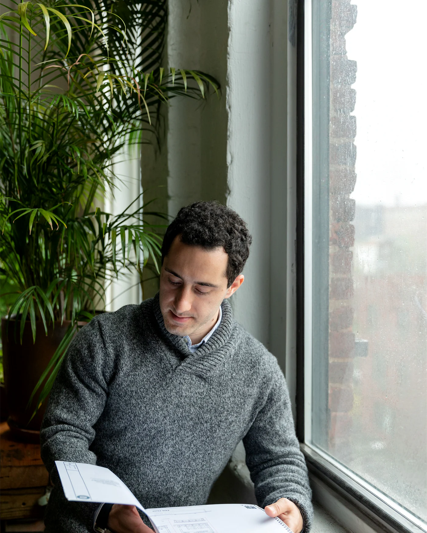 Adviser reading through case documents beside a large office window