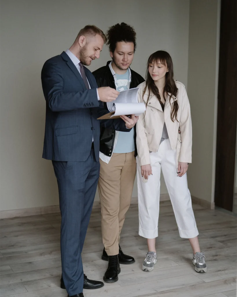 Adviser showing paperwork to a couple standing in a bright empty apartment