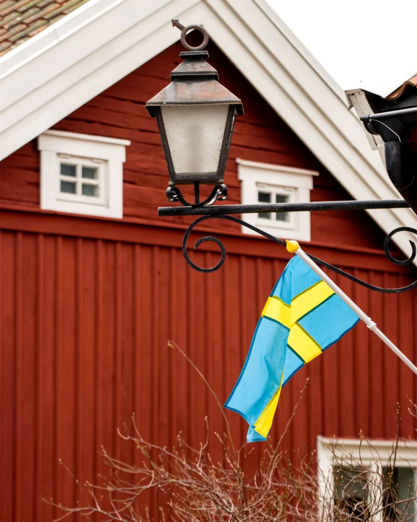 A Swedish flag on the wall of a traditional red wooden house