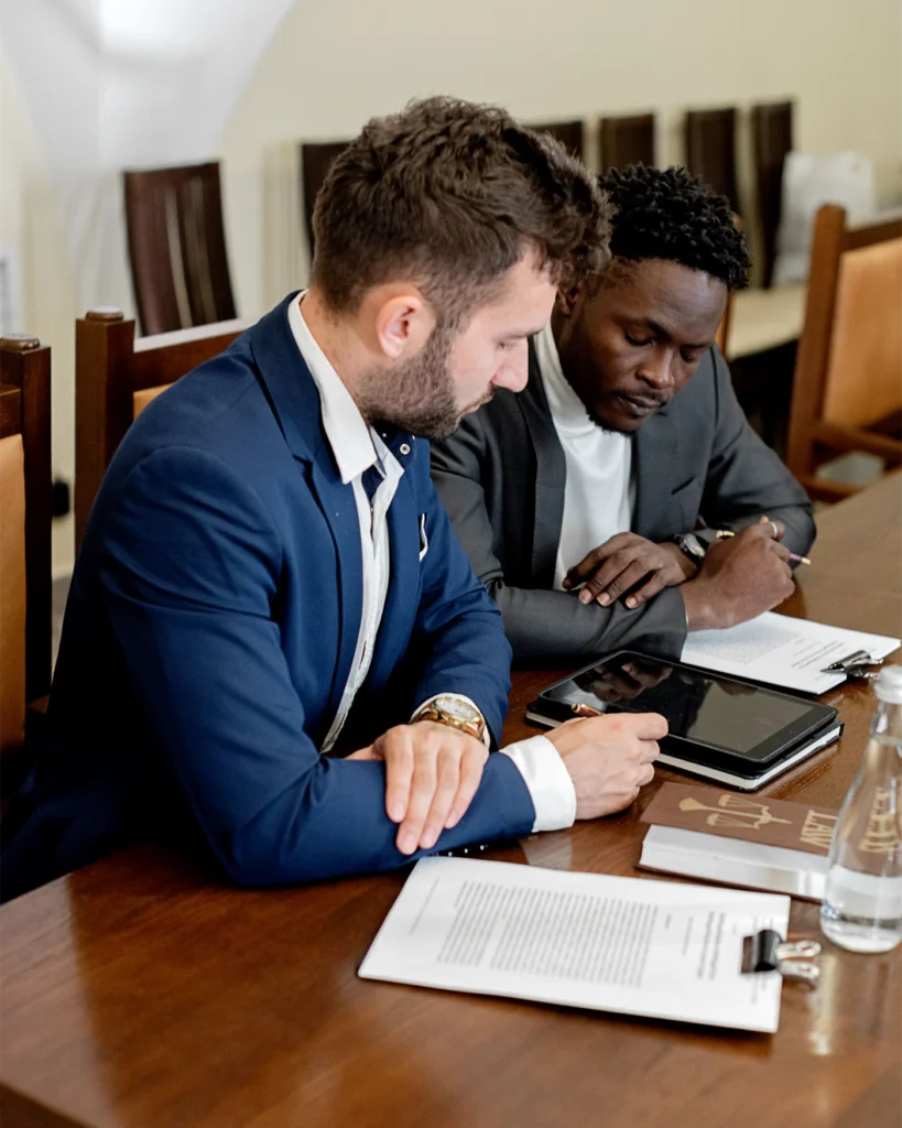 Two professionals working through documents at a boardroom table