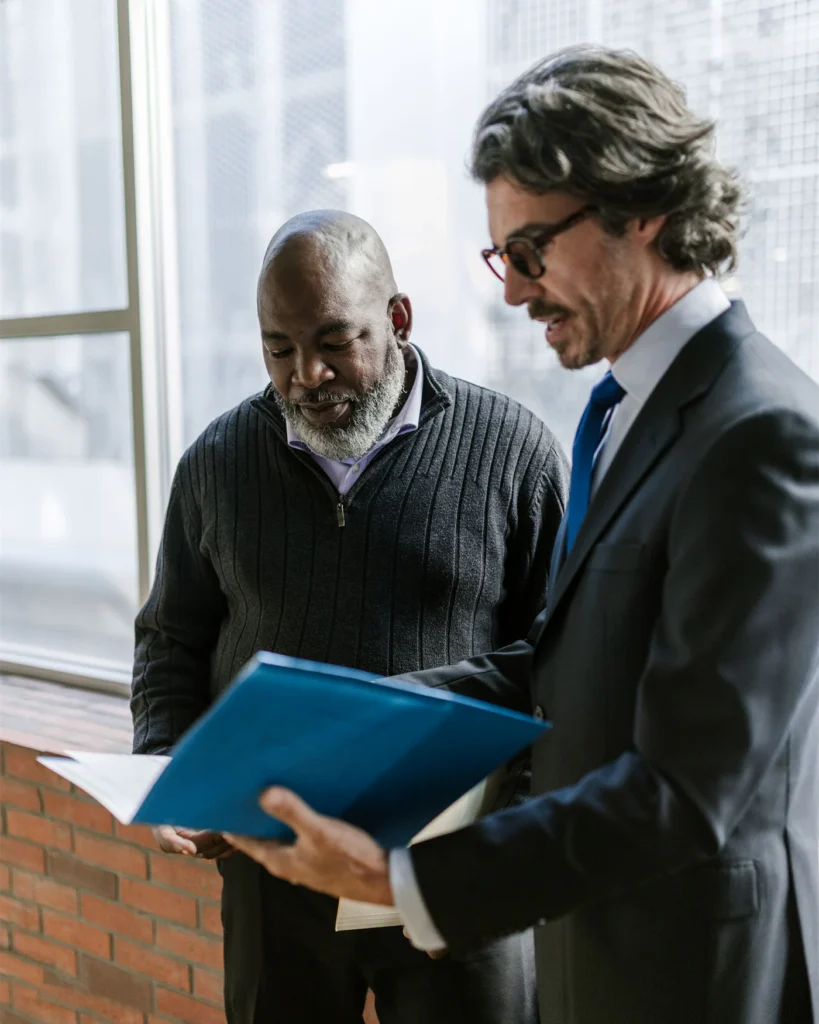 Senior executive and adviser reviewing a folder by an office window