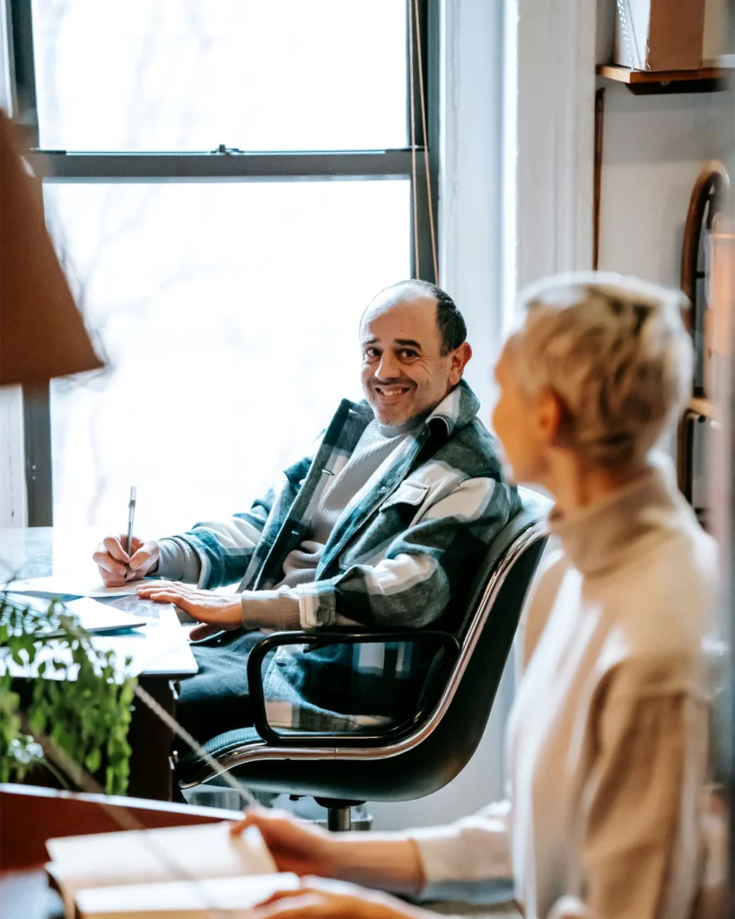 Two colleagues in discussion beside a tall office window