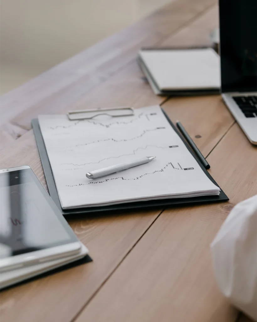 Meeting minutes on a clipboard beside a pen and laptop