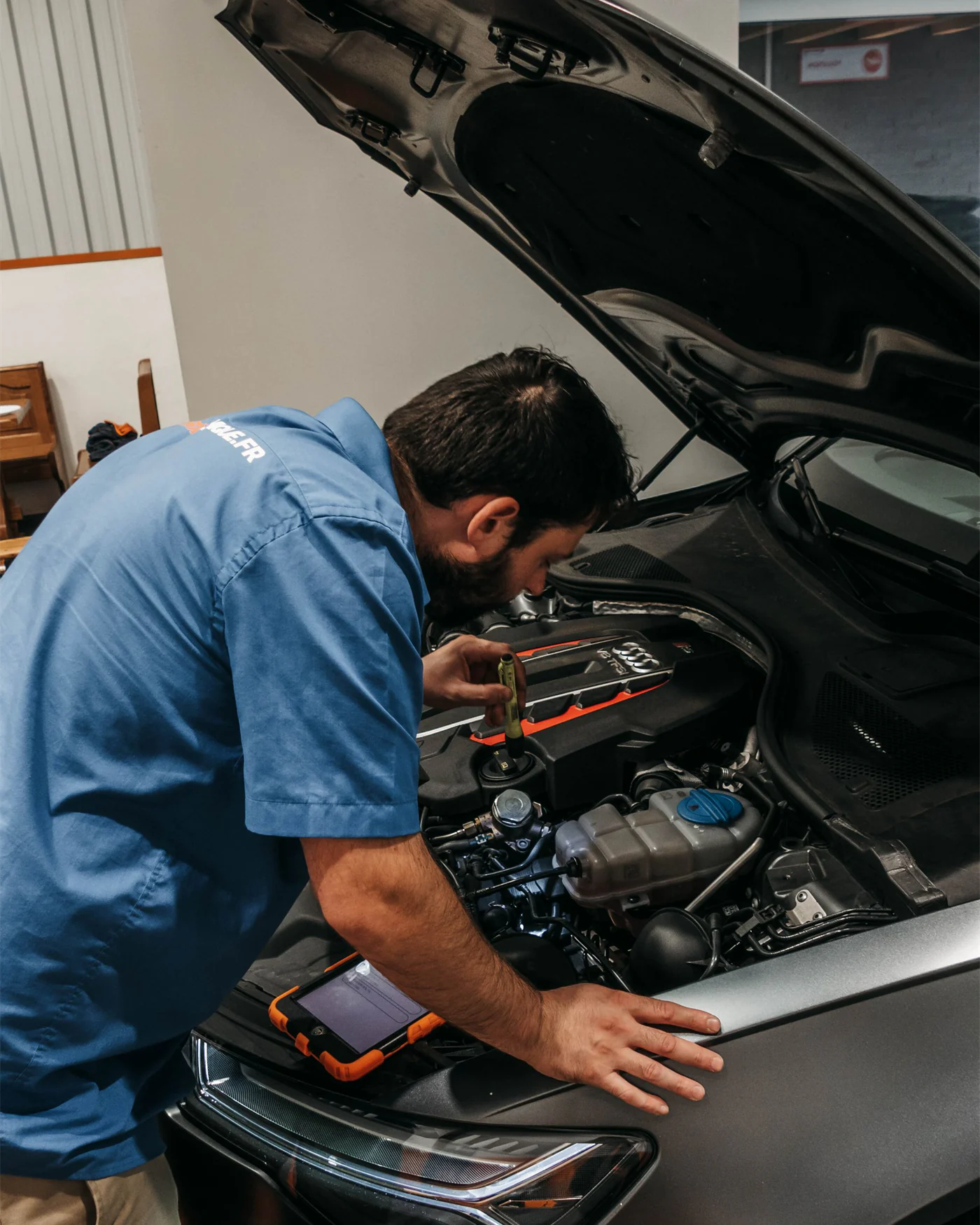 A mechanic inspecting an engine under the open bonnet of a car