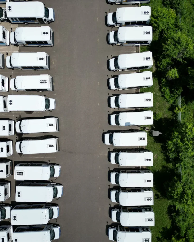 An aerial view of a commercial fleet standing idle in a depot beside forest