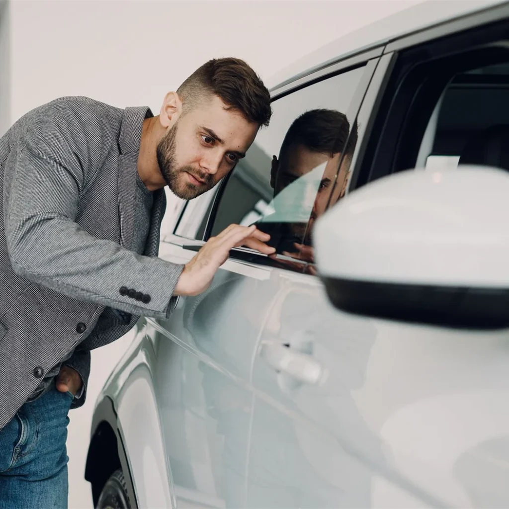 A buyer closely examining the bodywork of a used car