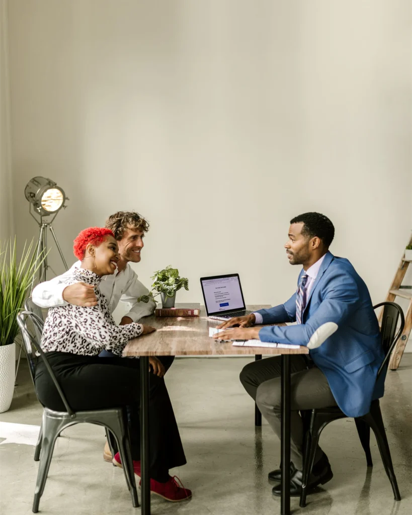 An adviser going through figures on a laptop with a young family across a table