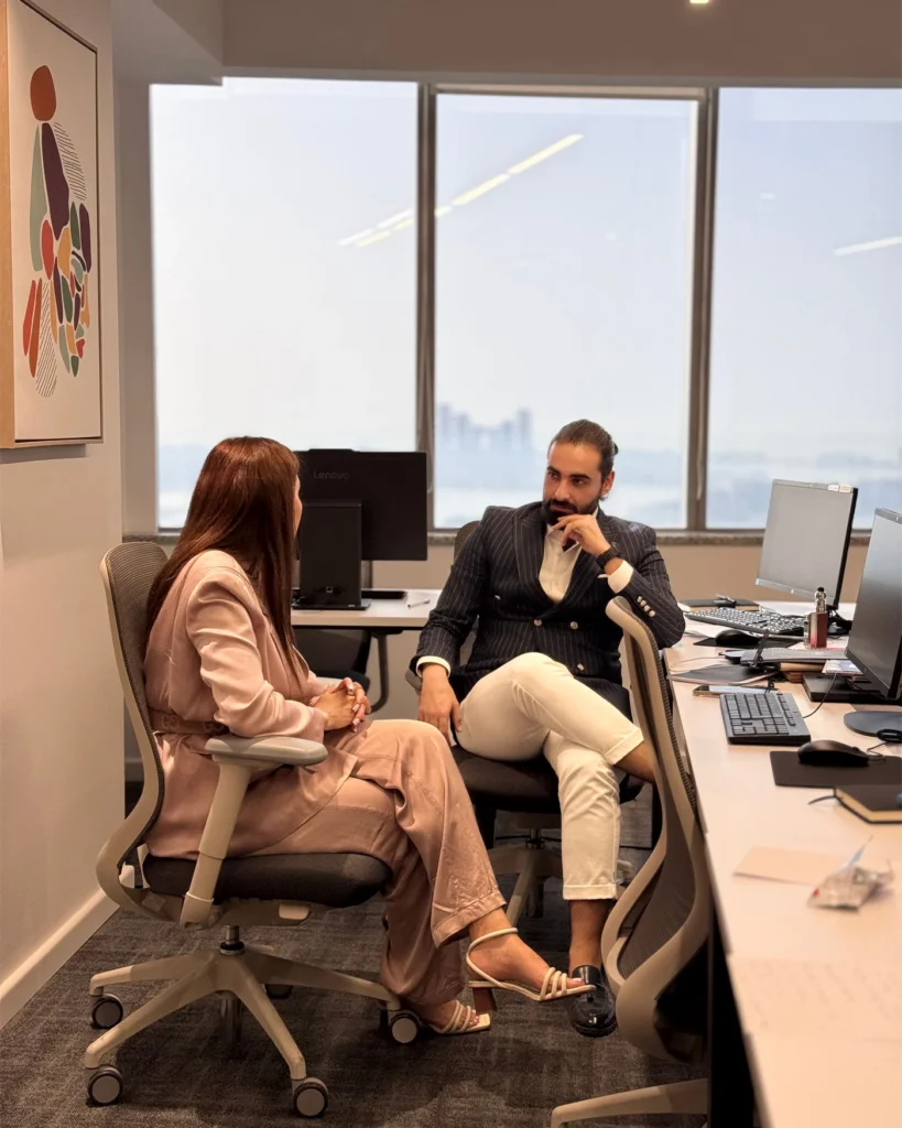 Two colleagues at work in a bright office with a city view
