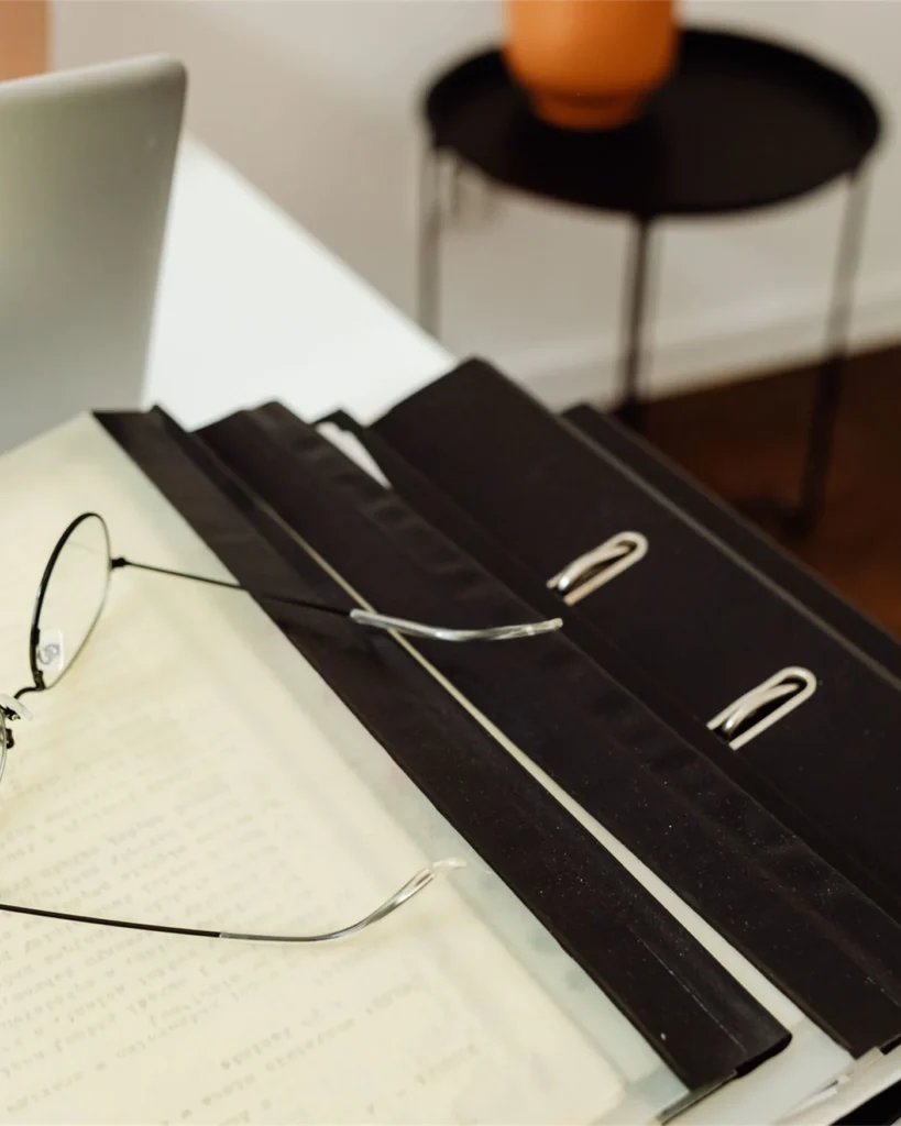 Workplace policy folders, reading glasses and papers on a desk