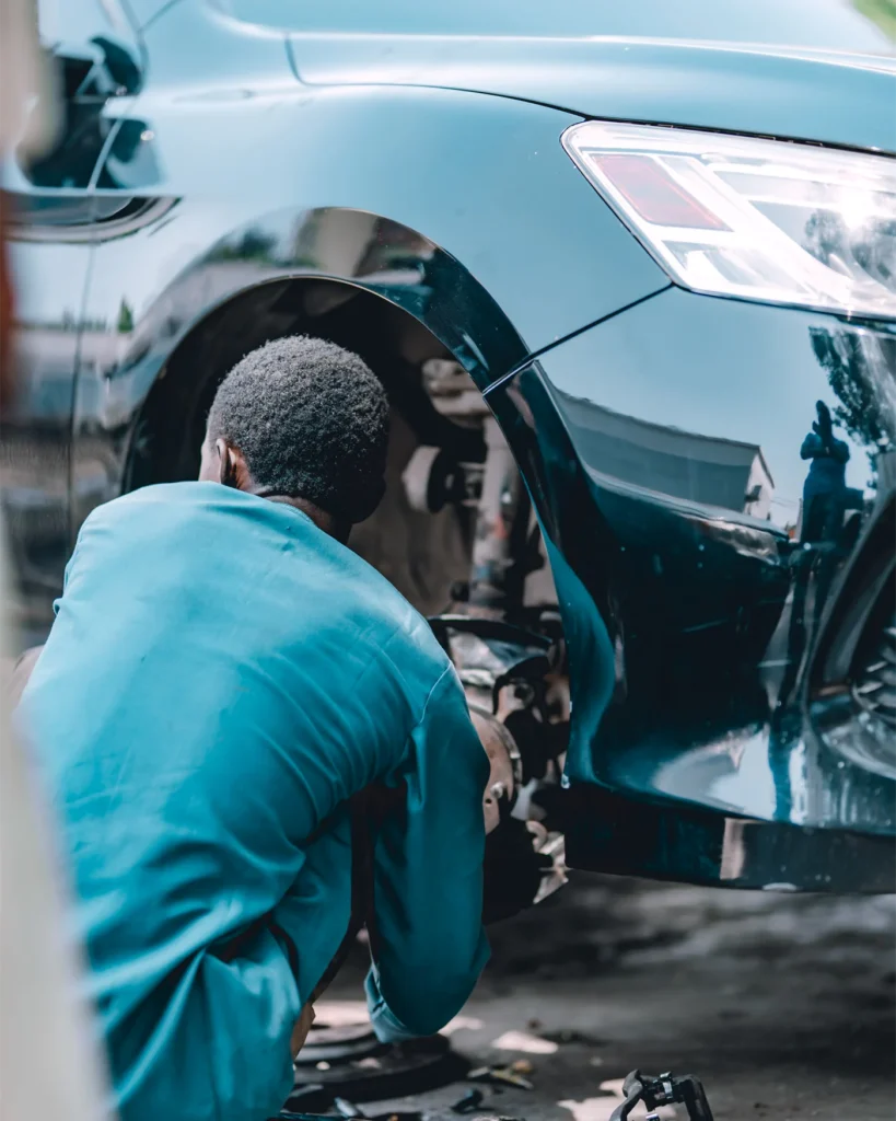 A mechanic working on a damaged front panel of a car in a workshop