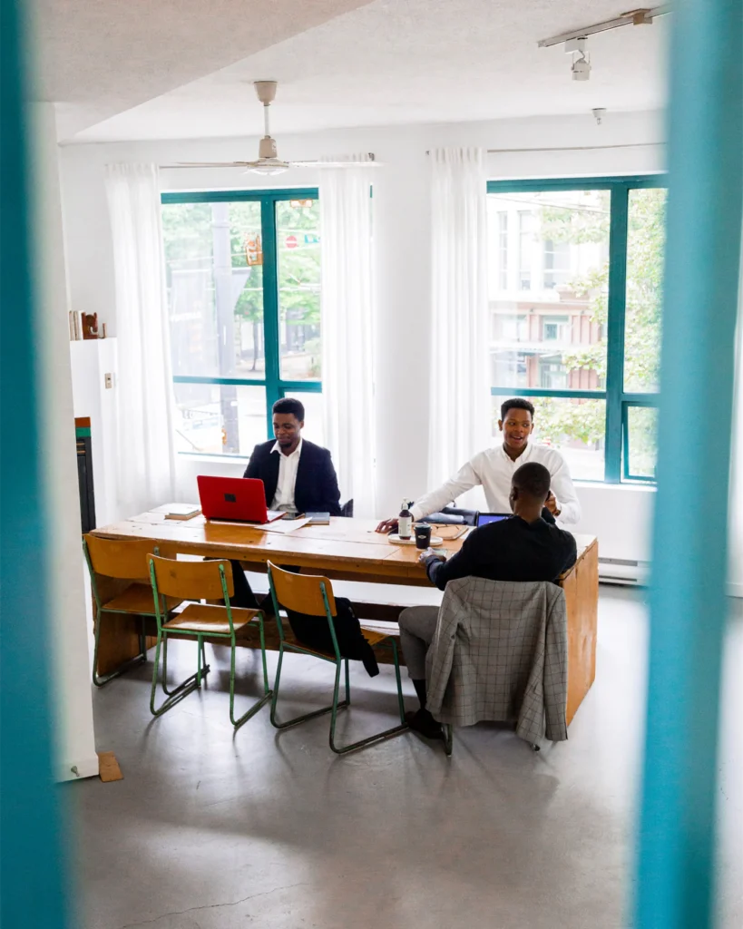 Two people working at a long table in a calm bright meeting room