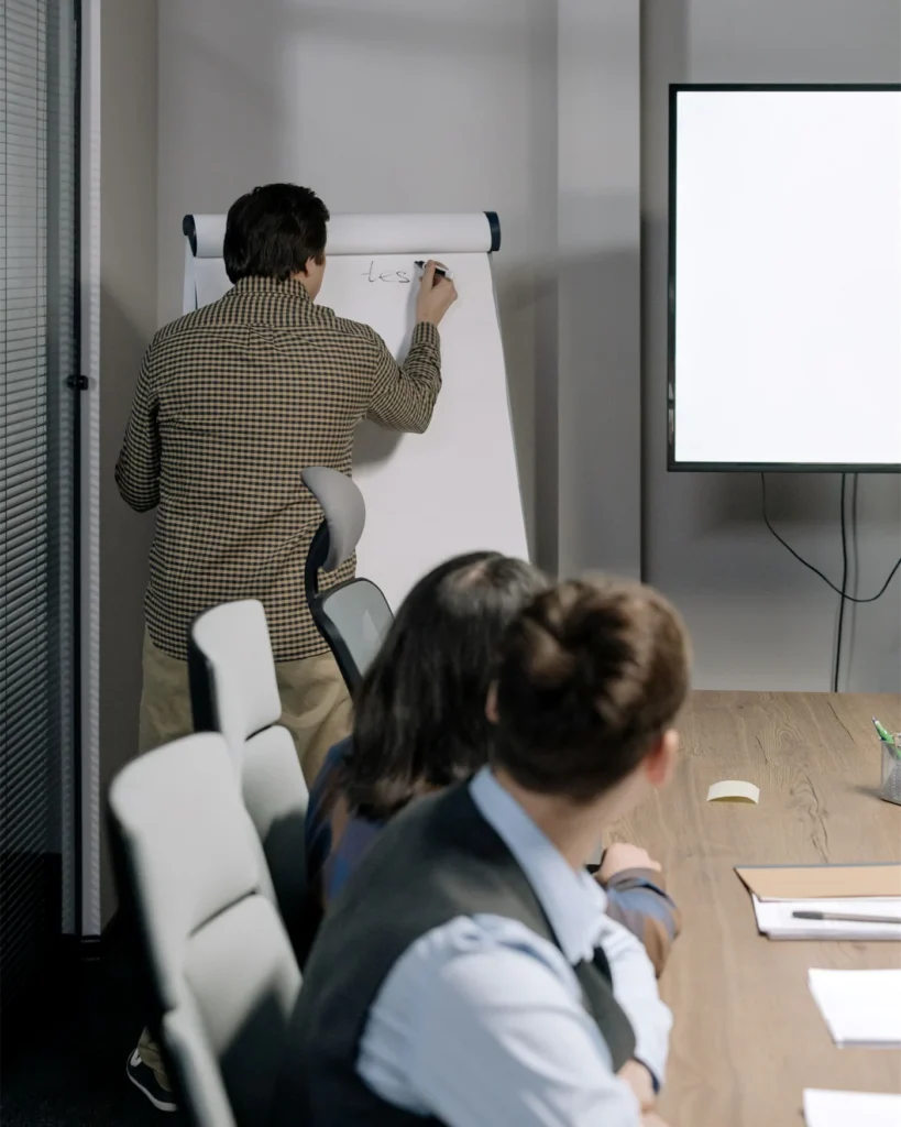 An adviser working through a point at a flipchart with colleagues
