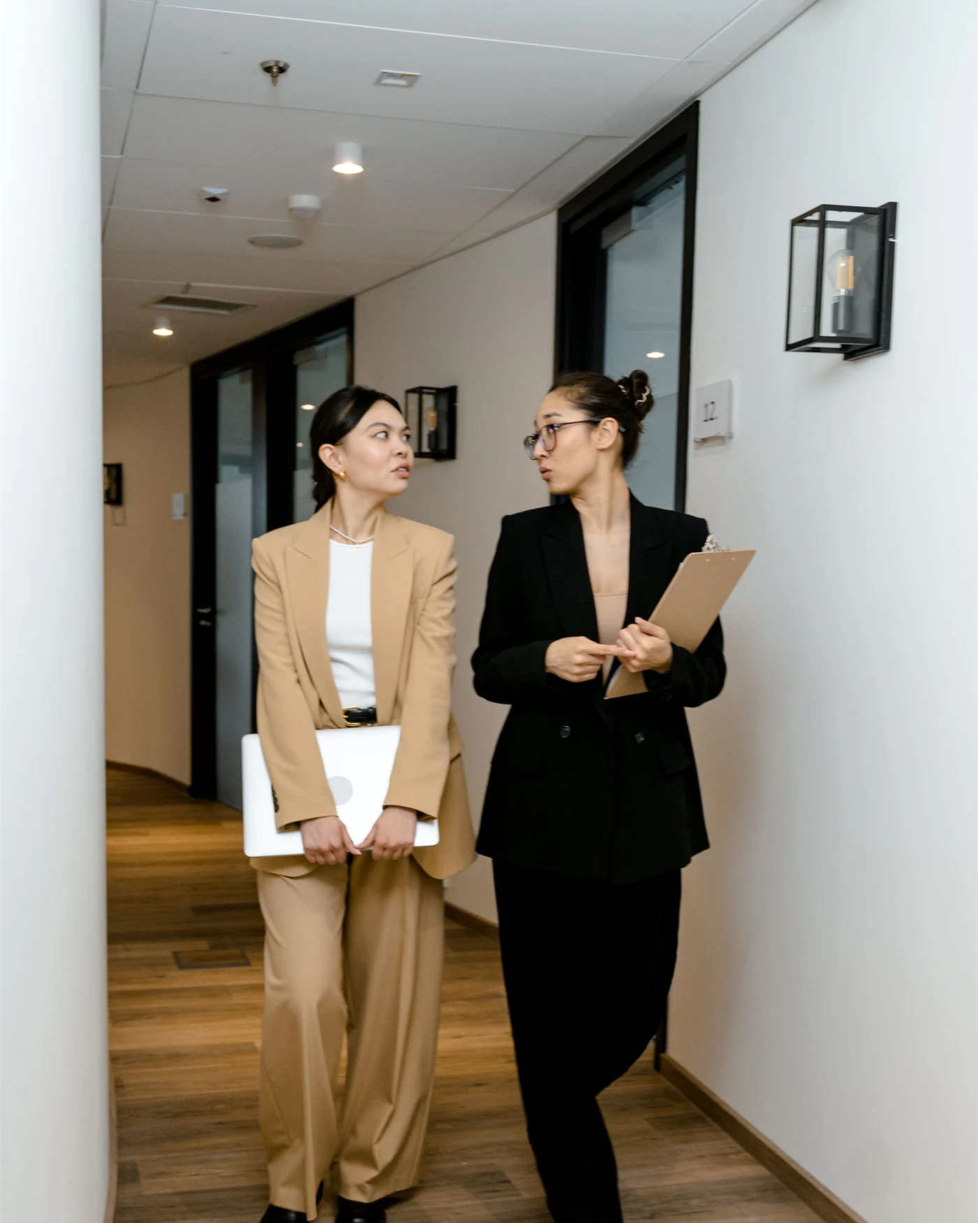 Two colleagues discussing a document together in a workplace corridor