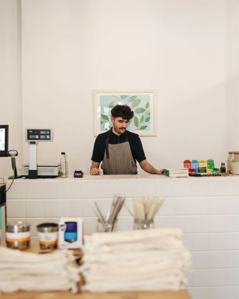 A shop owner behind the counter of a small store