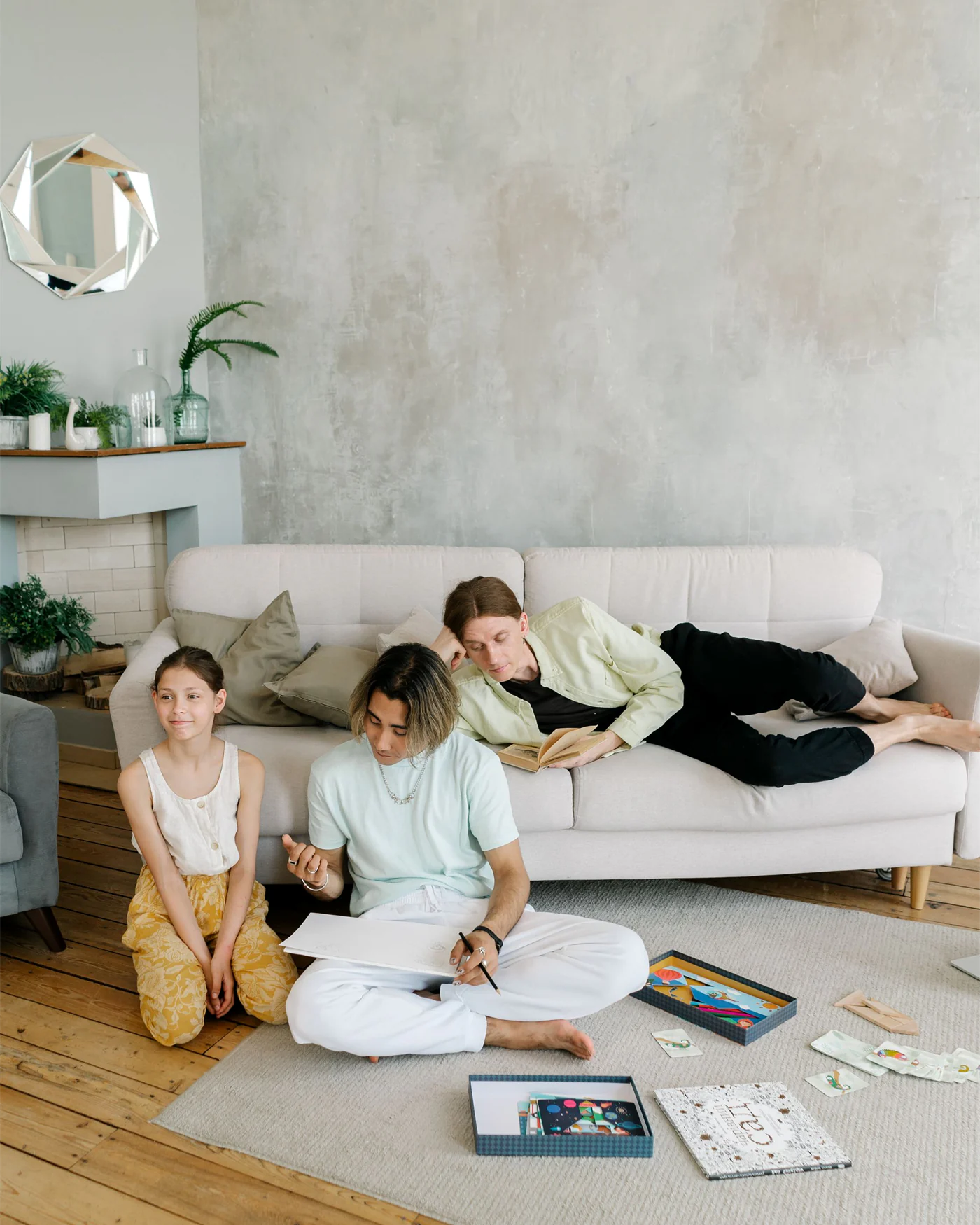 A family at home in a bright living room, drawing and reading together on the floor