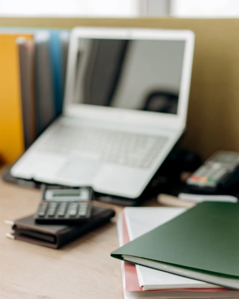 A working desk with case folders, a laptop and a calculator