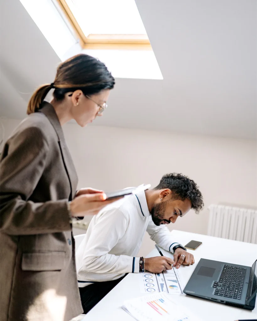 Adviser and colleague working together at a desk under a skylight