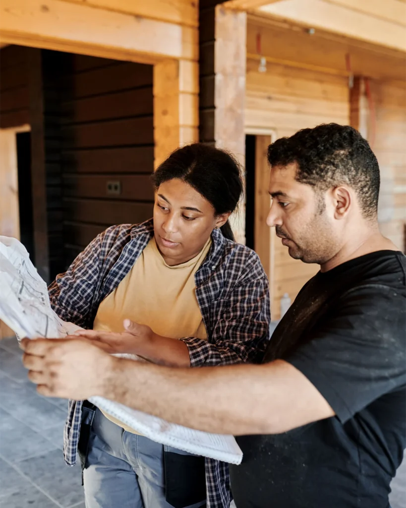 Two professionals examining building plans inside a timber building