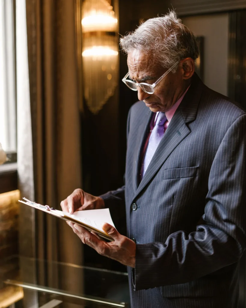 A senior professional reading paperwork beside a window