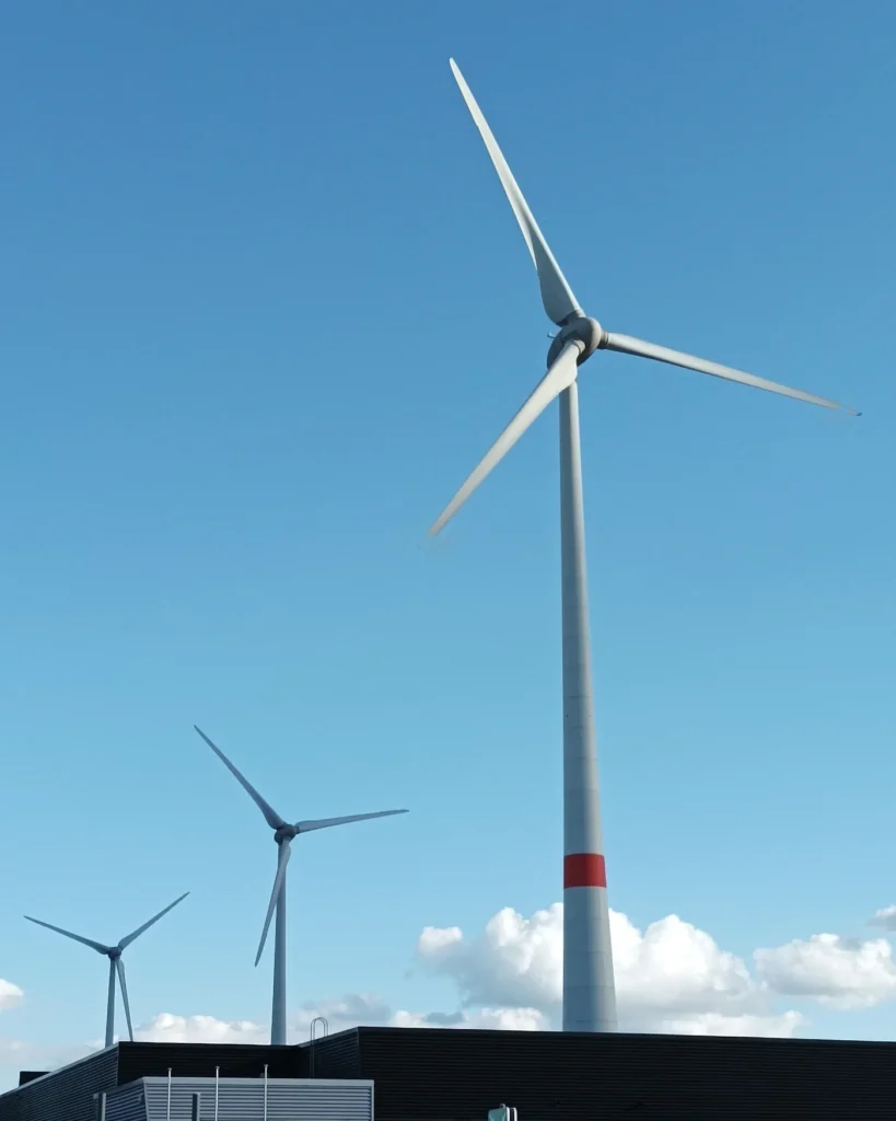 Wind turbines rising above an industrial site under a blue sky