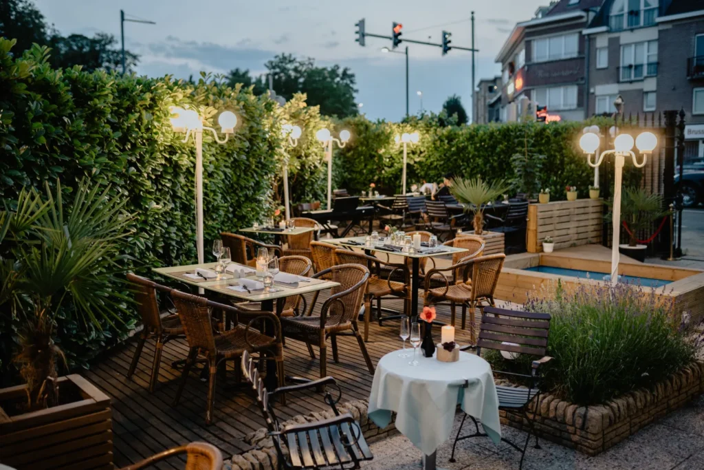 Outdoor cafe tables and metal chairs arranged beside a brick building