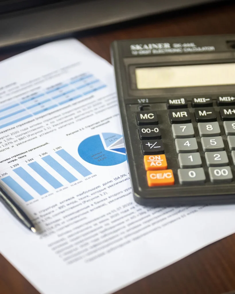 A calculator and pen beside a financial report with charts