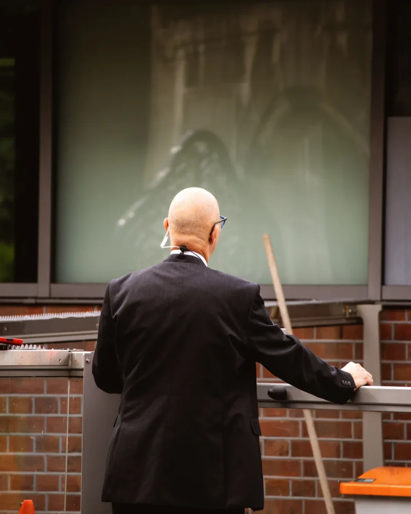 A security guard in a dark suit standing outside a building