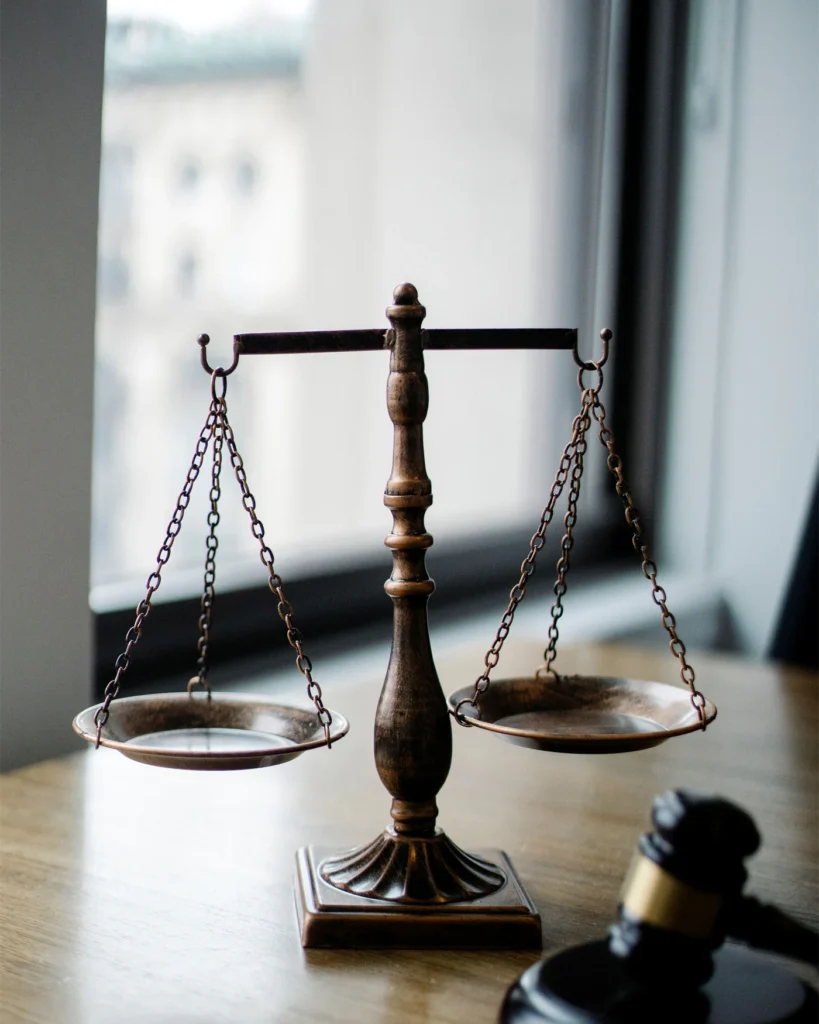 Brass scales and a gavel on a lawyer desk beside a bright window