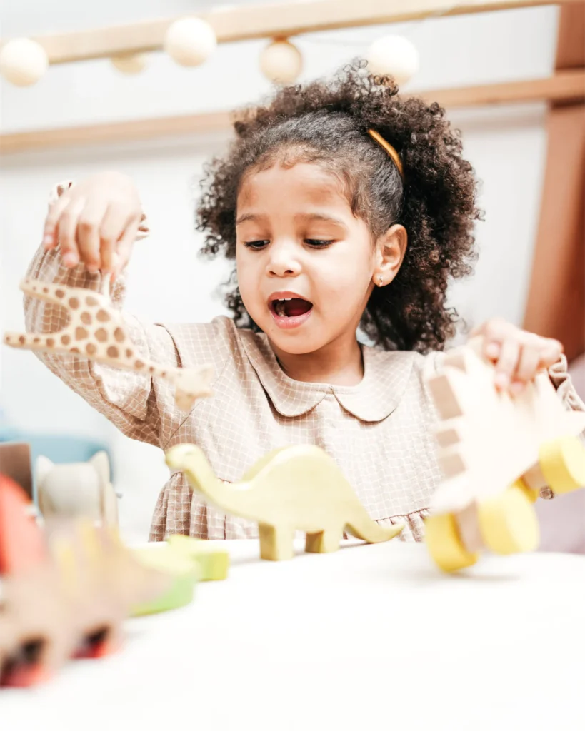 A young child playing with wooden animal toys