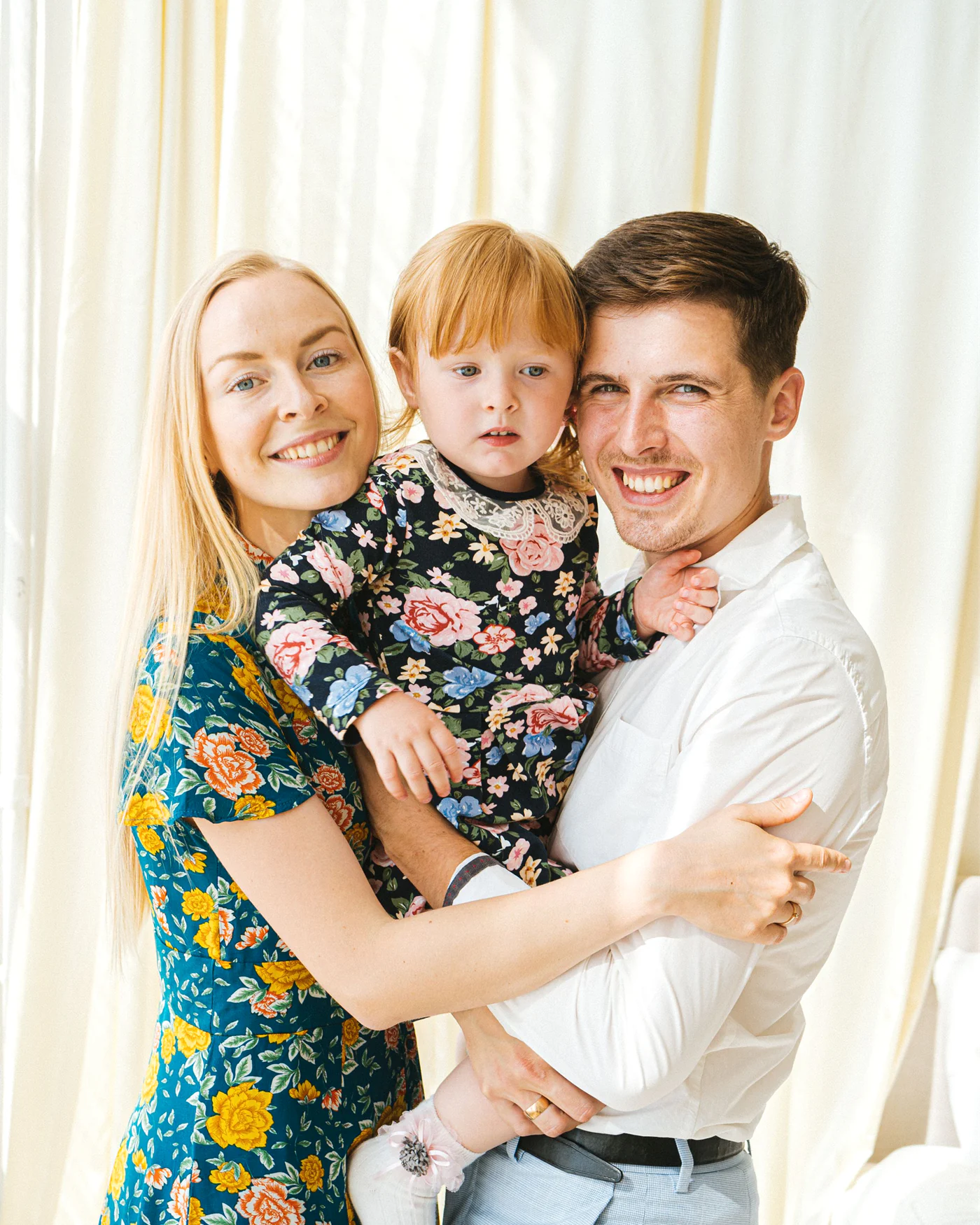 Two parents holding their young child at home